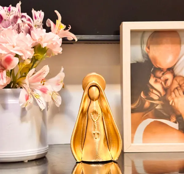 Nossa Senhora dourada impressa em 3D ao lado de porta-retrato