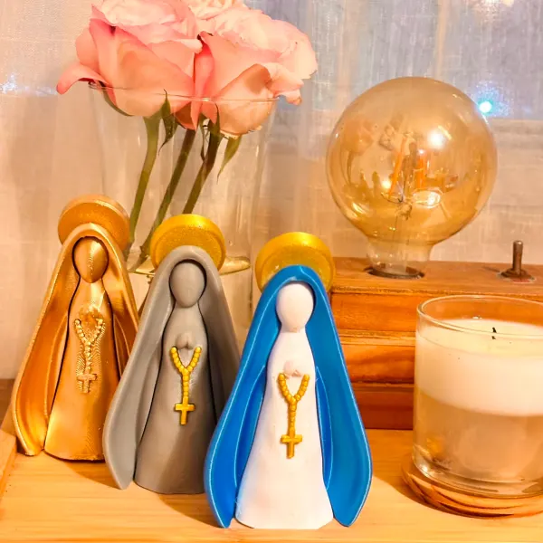 Três imagens de Nossa Senhora impressas em 3D nas cores dourado, cinza e azul